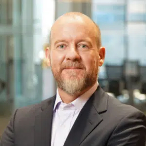 Headshot of a man with a beard in a dark suit